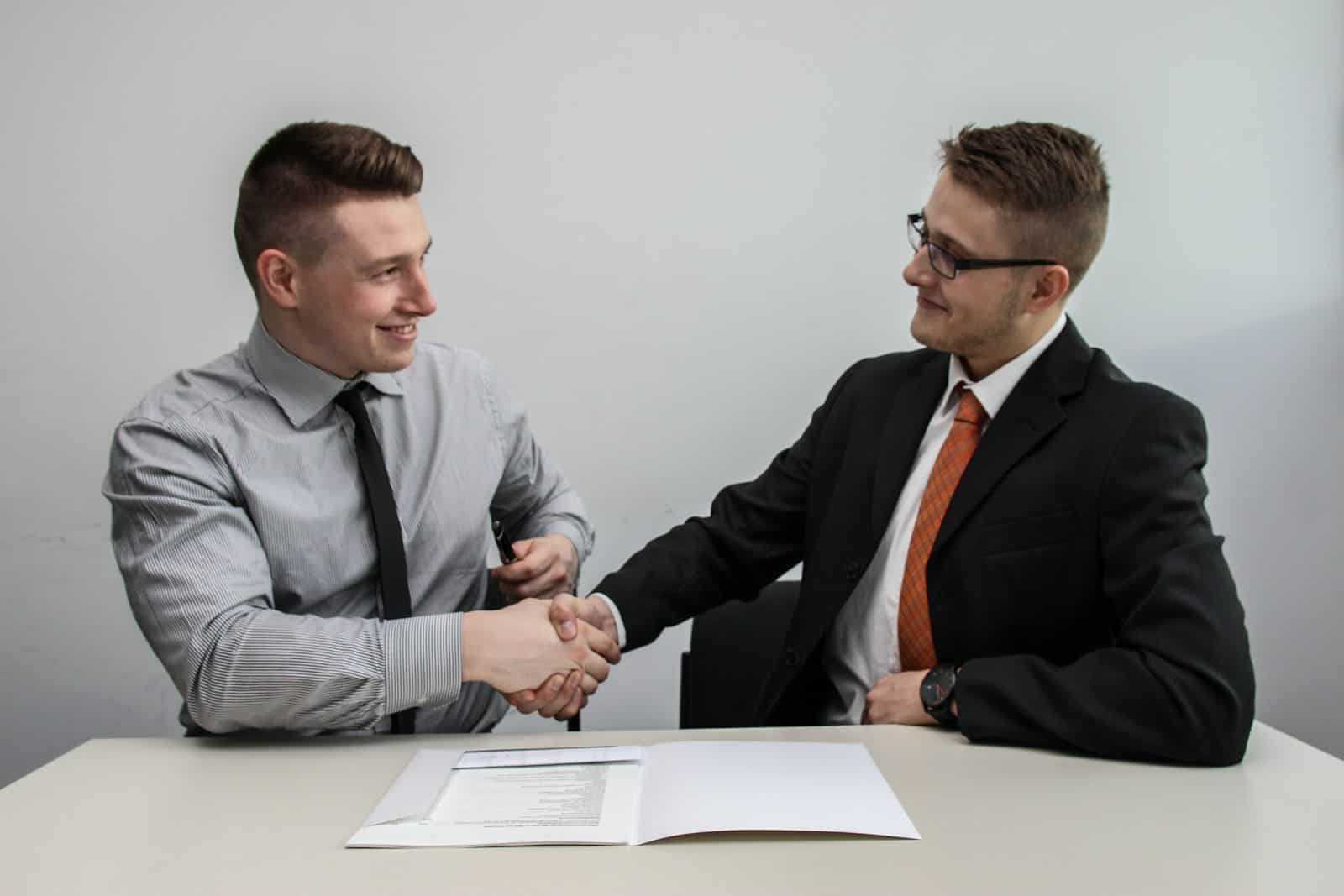 two men facing each other while shake hands and smiling