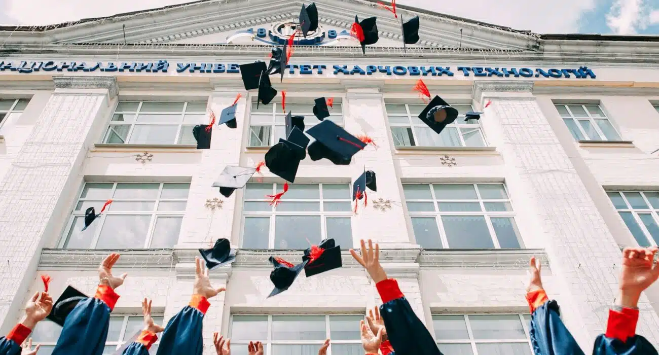 group of fresh graduates students throwing their academic hat in the air