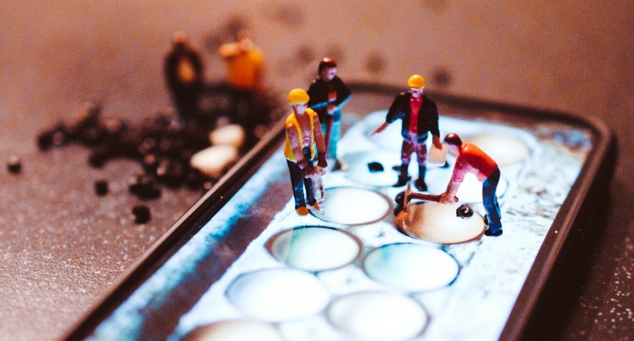 tiny model construction workers, working on a mobile phone screen